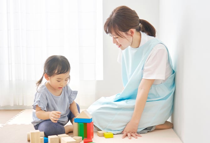 おままごとで遊ぶ子供と見守る保育士